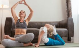 Free A grandmother and granddaughter enjoy a yoga session together in a cozy living room setting. Stock Photo